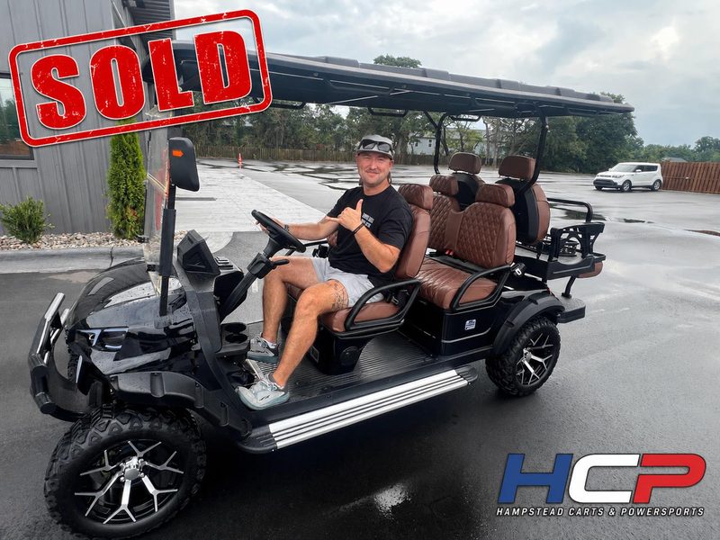 Customer at the wheel of a black golf cart with brown seats