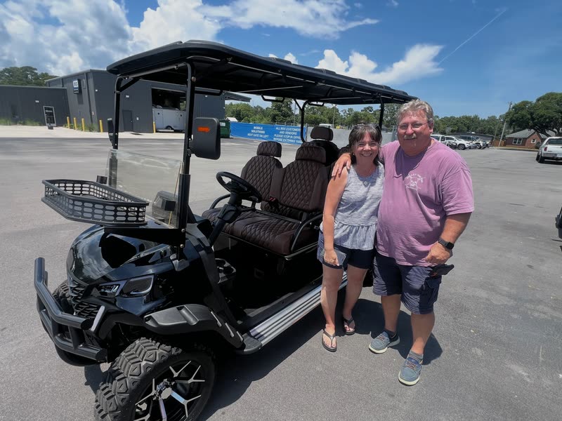 Customers standing beside their new lifted six-seat golf cart with diamond-stitched seats