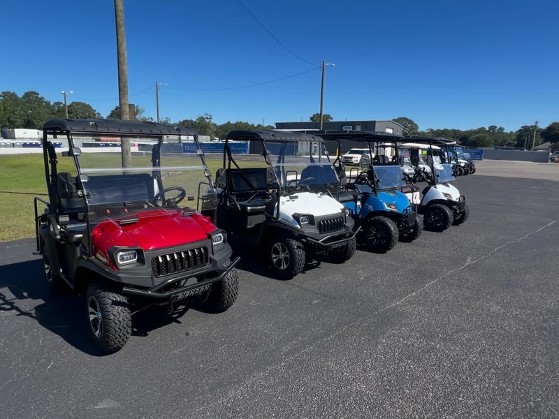 Side-by-sides and golf carts lined up in the sun