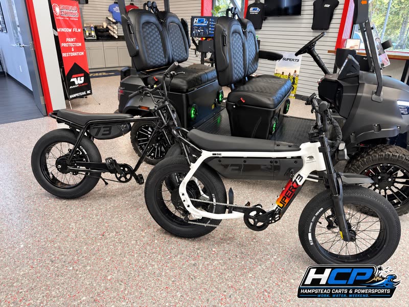 White Super73 e-bike next to a golf cart in the showroom